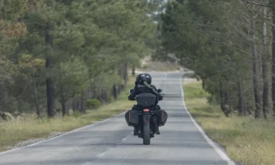 Rider and pillion in full protective kit on a tree-lined country road