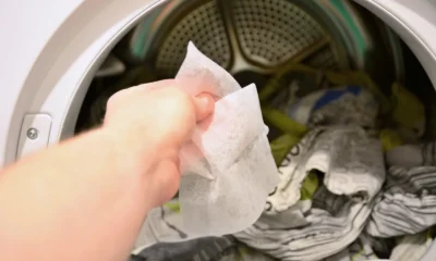 Hand putting a dryer sheet into a tumble dryer