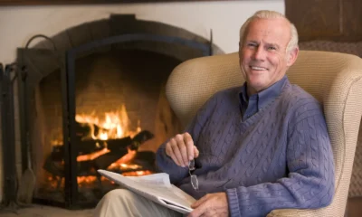 Man relaxing in an armchair by a lit fireplace