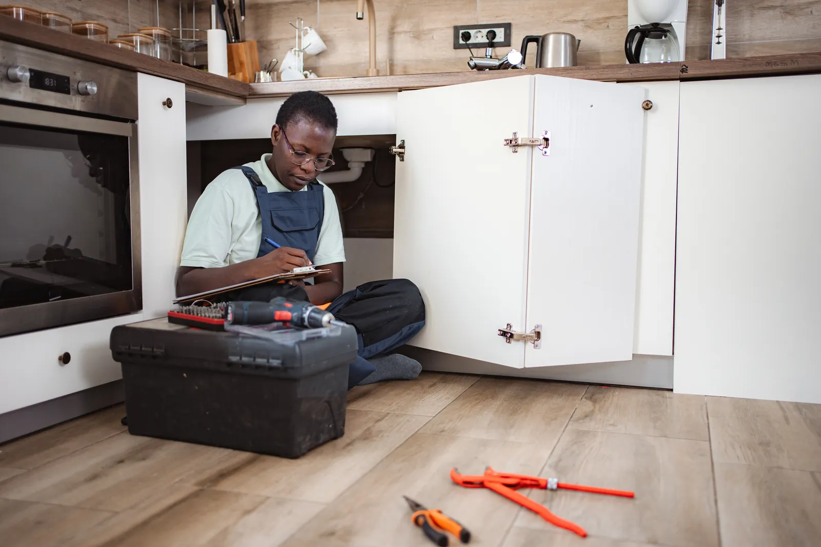 Plumber checking the pipes and stop tap under a kitchen sink