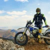 Rider in off-road kit and tall protective boots beside a trail bike