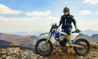 Rider in off-road kit and tall protective boots beside a trail bike