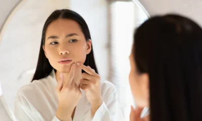 Woman checking her skin for spots and scars in a bathroom mirror