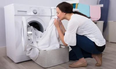 Woman smelling freshly washed laundry by a washing machine
