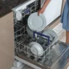 Woman taking a clean plate out of a dishwasher