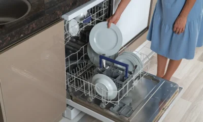 Woman taking a clean plate out of a dishwasher
