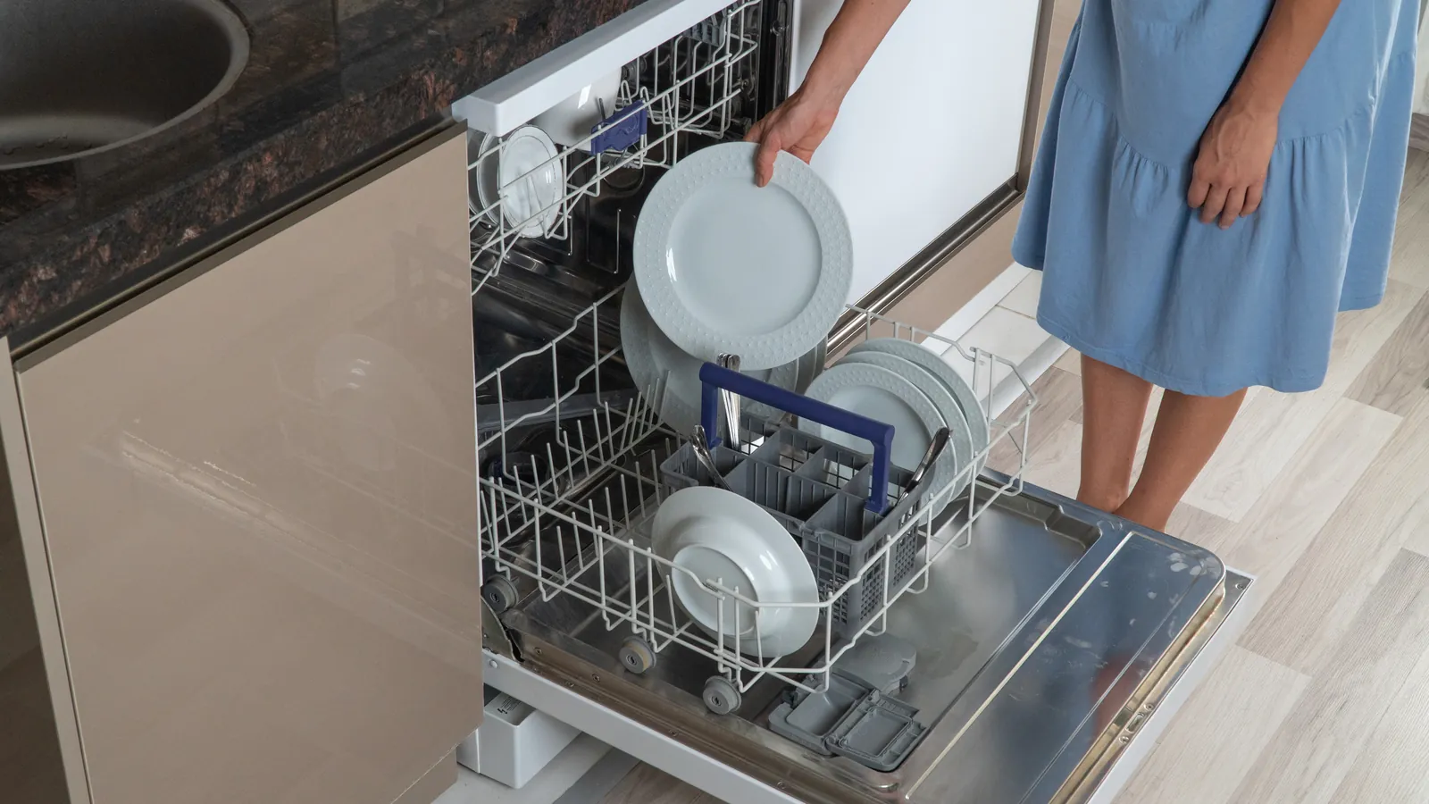 Woman taking a clean plate out of a dishwasher