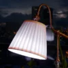Table lamp with a pleated shade glowing by a window on a dark evening